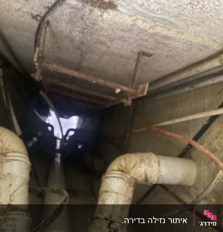 צינורות מתכת חלודים בתקרה עם נזילות מים